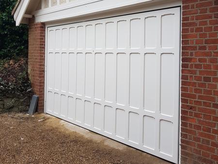 White timber up and over electric door with panelled design.